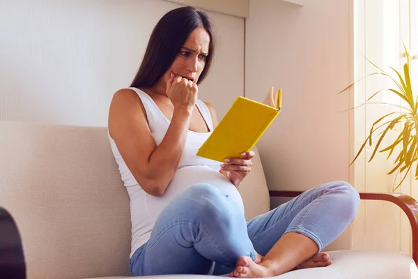 Frightened pregnant woman reading book — Stock Photo, Image