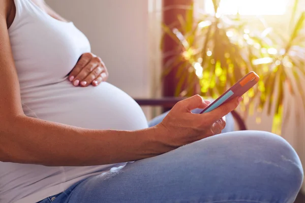 Mains de femme enceinte textos au téléphone — Photo