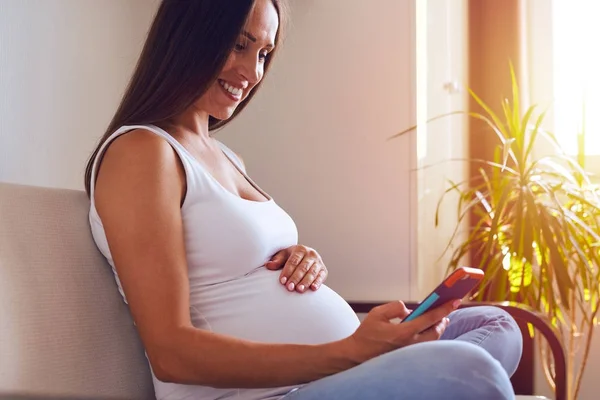 Mosolyogva terhes nő küldött üzenetek telefonon keresztül — Stock Fotó