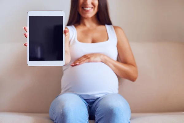 Mujer mostrando tableta mientras está sentado en el sofá —  Fotos de Stock