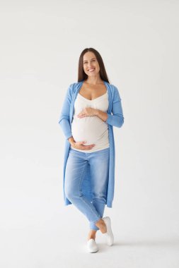 Kameraya poz göbek üzerinde elleriyle neşeli hamile kadın 