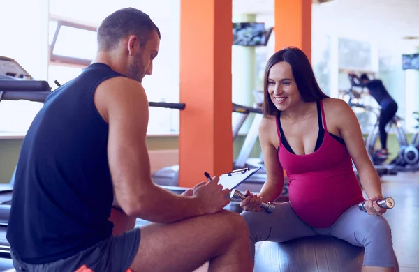 Zwangere vrouw praten met personal trainer — Stockfoto