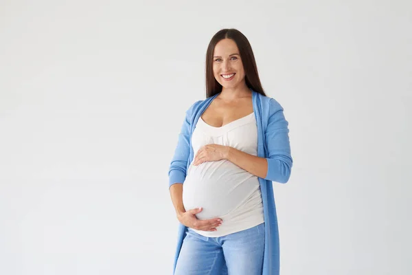 Jovem grávida posando com as mãos na barriga — Fotografia de Stock