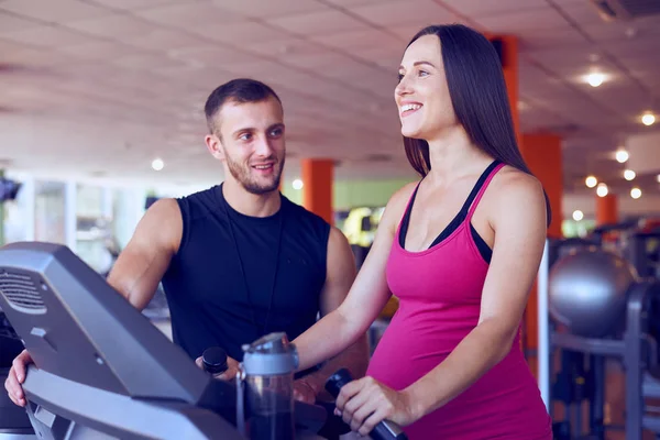 Mujer embarazada feliz corriendo en la cinta de correr bajo el control del perso — Foto de Stock