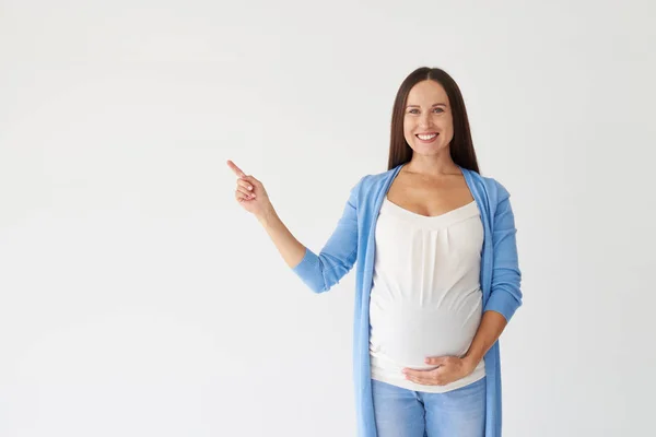Młoda kobieta w ciąży, wskazując na miejsce — Zdjęcie stockowe