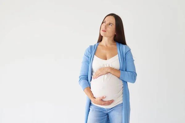 Mujer reflexiva cogida de la mano en el vientre embarazada y mirando awa —  Fotos de Stock