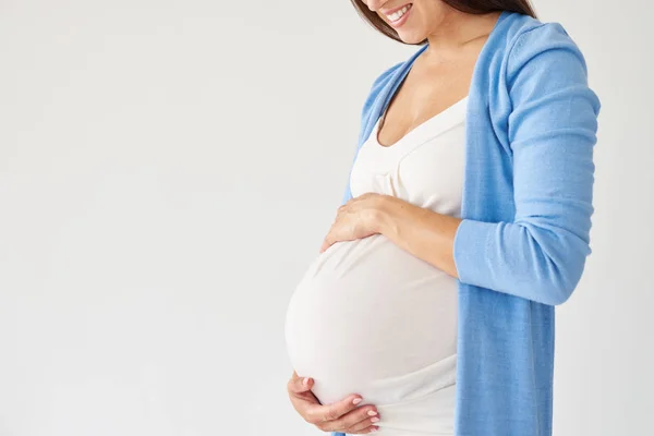 Mulher segurando barriga grávida contra fundo branco — Fotografia de Stock