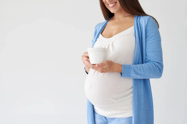 妊娠中の女性が白い背景がある上分離された紅茶のカップを穴かがり — ストック写真