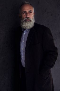 Bir yerde karanlık studi poz bakan dalgın sakallı adam