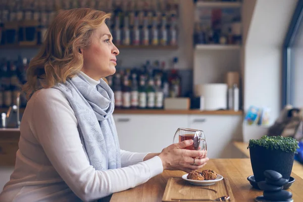 Erfreute reife Frau mit Tasse Tee sitzt im Café — Stockfoto