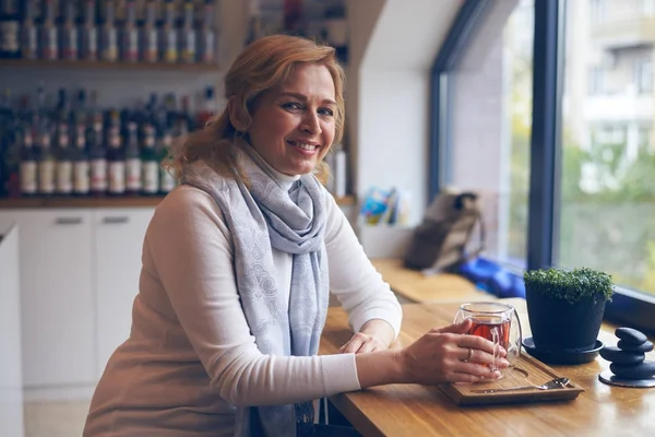 Pleased mature woman enjoying flavor tea in cafe — Stock Photo, Image