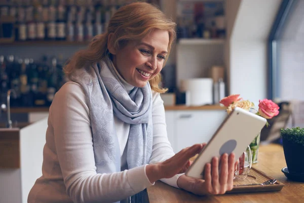 Smiley mature woman using digital tablet in cafe — Stock Photo, Image