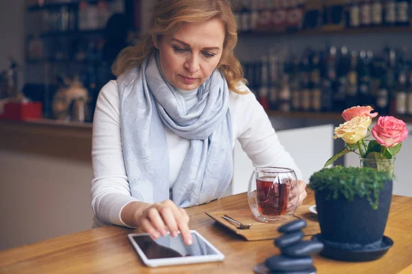 Thoughtful mature woman using tablet with black screen — Stock Photo, Image