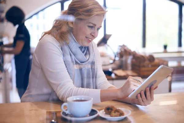 Gelegenheitsreife Frau arbeitet im Café an Tablet — Stockfoto