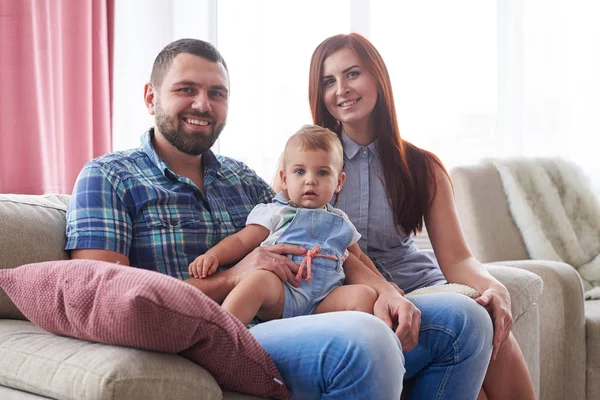 Счастливая улыбающаяся семья из трех человек сидит на диване — стоковое фото