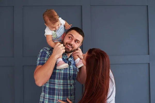 Roliga familj på tre poserar mot bakgrund — Stockfoto