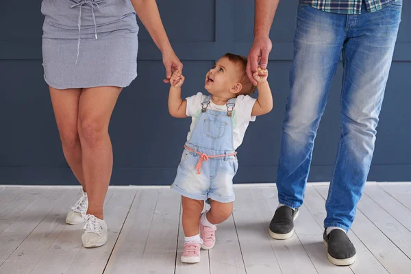 Hübsche kleine Tochter hält Elternhände beim Gehen im Rooo — Stockfoto