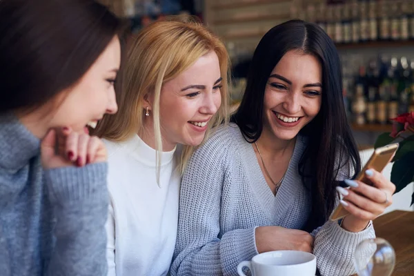 Drie jonge vrouwen foto's kijken met telefoon smiling — Stockfoto