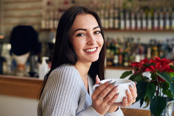 Mujer joven caucásica sosteniendo taza de café en la cafetería — Foto de Stock