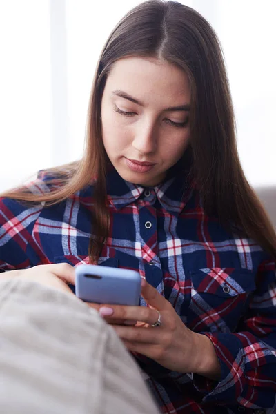 在沙发上使用电话的集中的女孩 — 图库照片