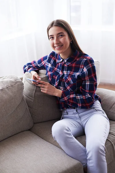 Flicka med telefon på soffan hemma — Stockfoto