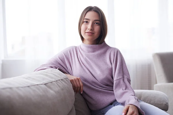 Fiduciosa bella ragazza seduta sul divano nel suo appartamento — Foto Stock