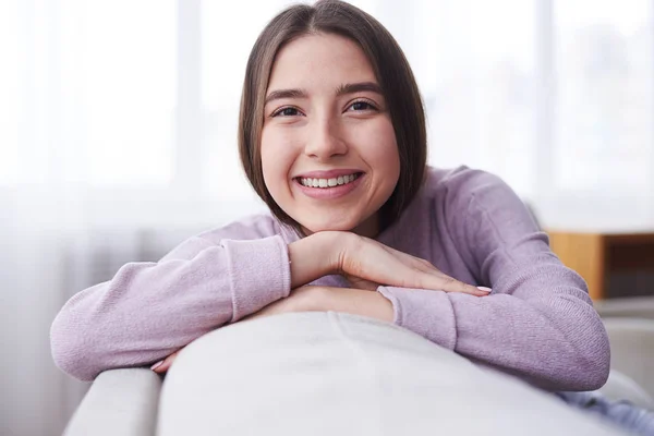 Boldog lány visel támaszkodva kanapé kényelmes pulóver — Stock Fotó