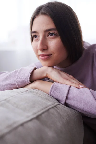 Ragazza sognante in maglione cercando lato, seduto sul divano — Foto Stock