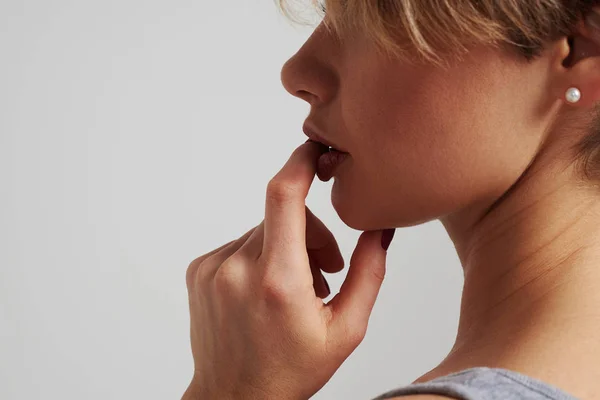 Mujer joven sosteniendo el dedo en sus labios — Foto de Stock