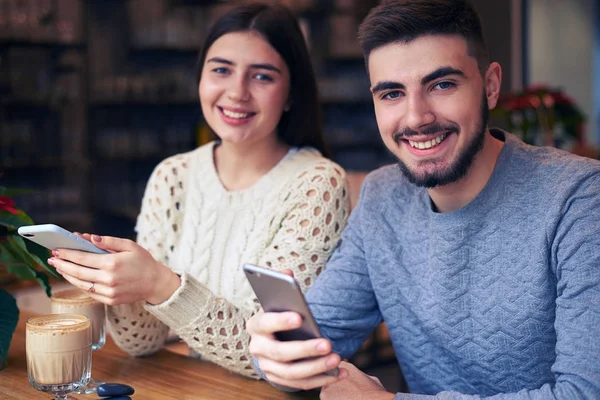 快乐的年轻夫妇在电话上发短信在咖啡馆约会 — 图库照片