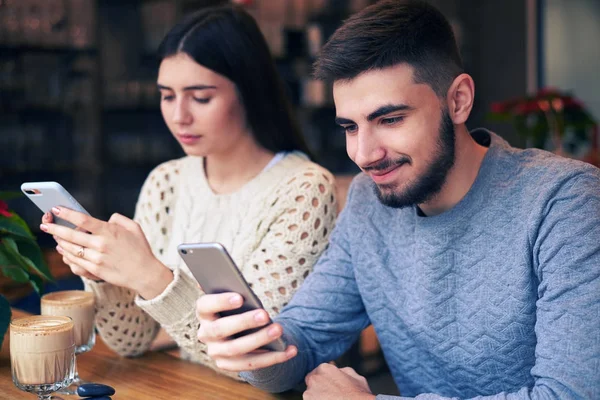 Позитивная пара, использующая телефоны в кафе во время свиданий — стоковое фото