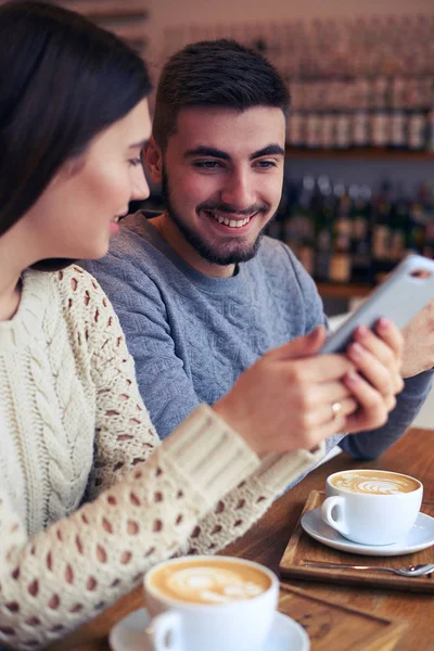 Krásný pár pomocí telefonů v kavárně — Stock fotografie