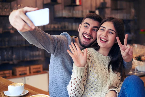 Улыбающаяся молодая пара делает селфи на смартфоне — стоковое фото