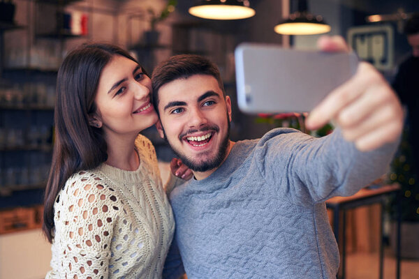 Cheerful man making selfie with his girlfriend at cafe