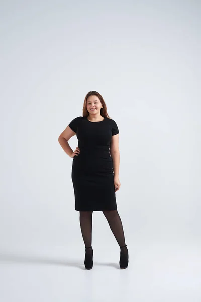 Trendige Frau im schwarzen Kleid steht isoliert auf dem Hintergrund — Stockfoto