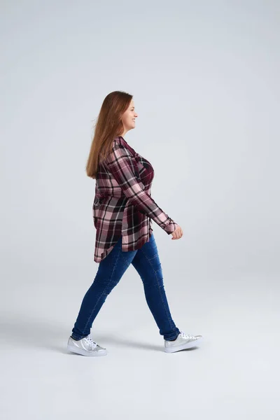 Jonge vrouw lopen in shirt en spijkerbroek — Stockfoto