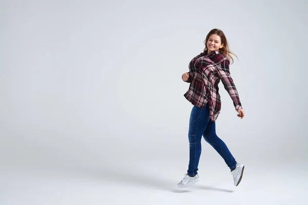 Ontspannen meisje springen in de lucht tijdens het wandelen in studio — Stockfoto