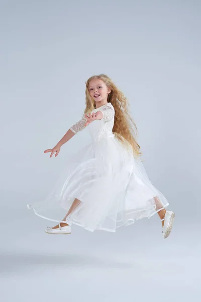 Schöne zarte blonde Mädchen im weißen Kleid springen — Stockfoto