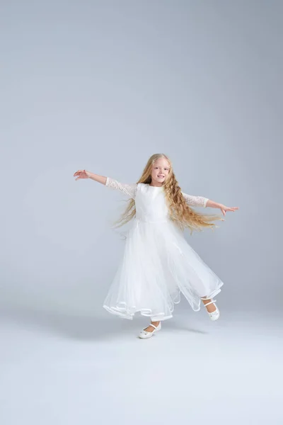 Cute blonde girl in white dress dancing at studio — Stock Photo, Image