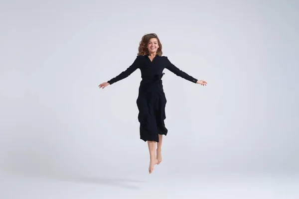 Cheerful young woman jumping up in the air — Stock Photo, Image