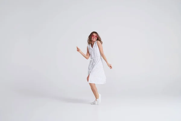 Menina atraente no vestido dançando em estúdio no fundo branco — Fotografia de Stock
