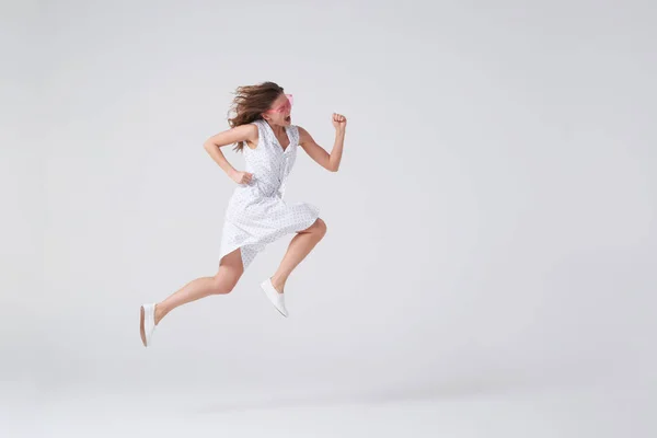 Chica alegre saltando en el aire sobre fondo en el estudio — Foto de Stock