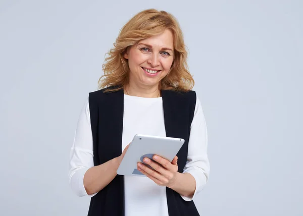 Mature blond with tablet pc smiling at camera — Stock Photo, Image