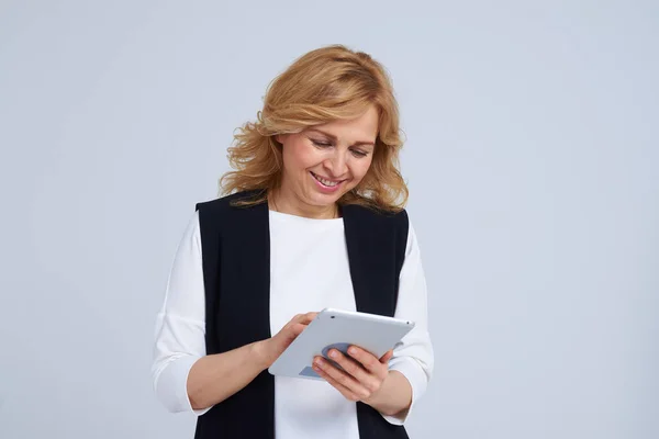 Reife Frau arbeitet mit Tablette und lächelt — Stockfoto