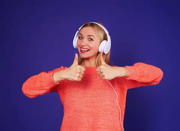 Žena v sluchátka ukazuje palec — Stock fotografie