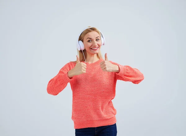 Позитивна блондинка в навушниках показує великі пальці вгору — стокове фото