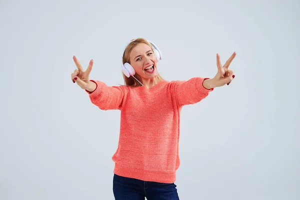 Mujer divertida en auriculares que muestran signo de victoria — Foto de Stock