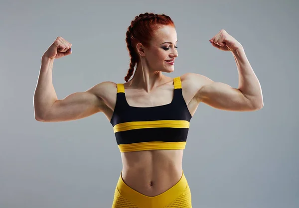 Sportswoman showing biceps with both hands — Stock Photo, Image