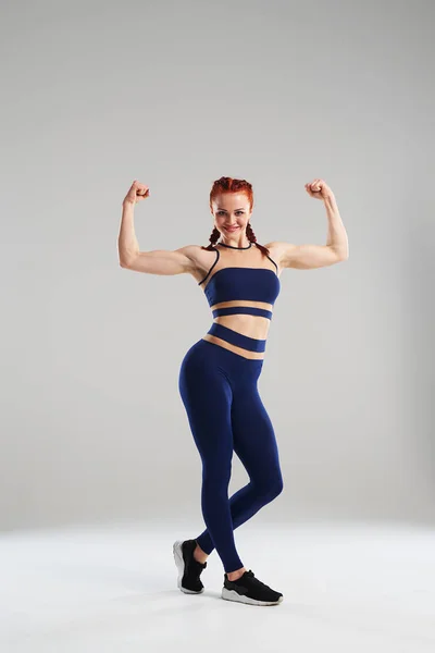 Femme de sport en bleu vêtements de sport montrant biceps — Photo