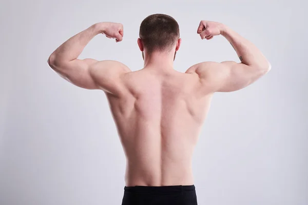 Sterke man zijn biceps van achter tonen — Stockfoto